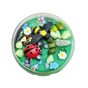 Rond doosje gevuld met groene sensorische klei, versierd met een plastic lieveheersbeestje, bij, kleurrijke steentjes, bloemetjes en kleine vlinders – een vrolijke lentetuin in miniatuurformaat.t5
